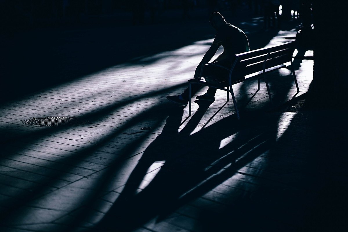 A dark park with a person sitting on a bench